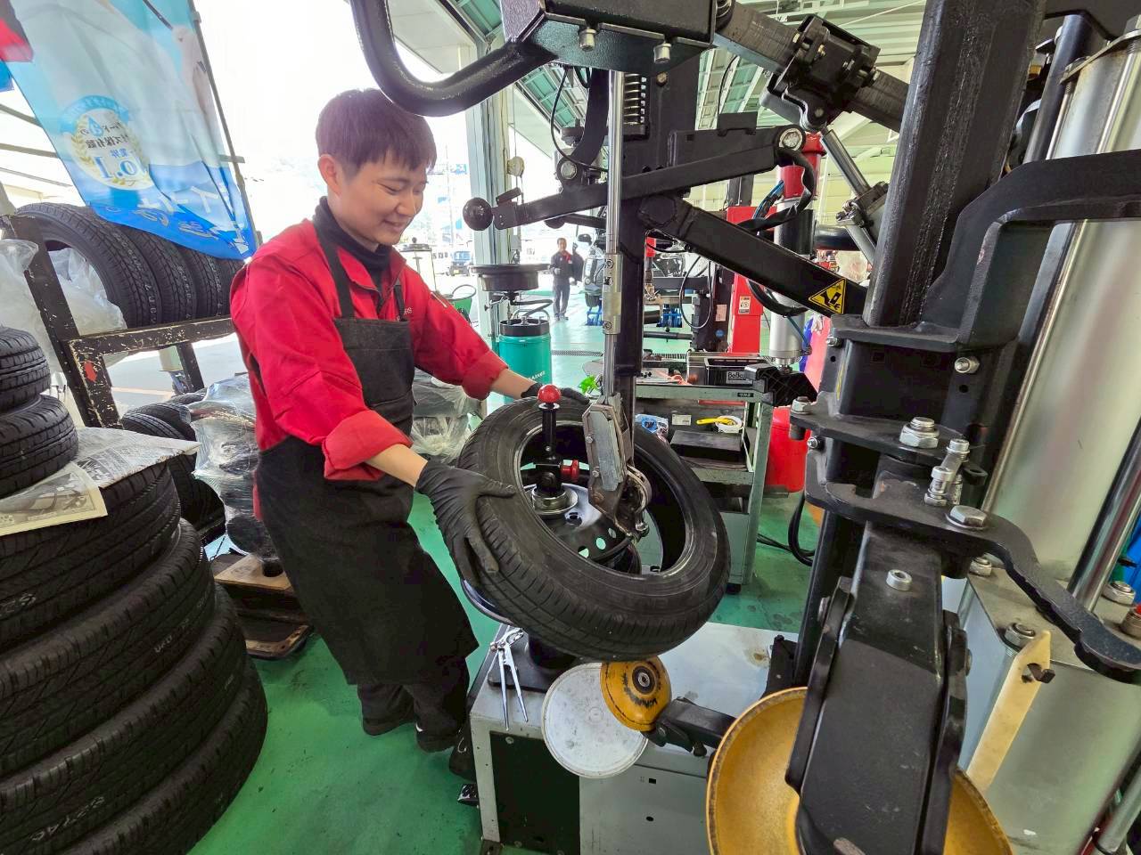 屋内の作業場で、スタッフが専用の機械(タイヤチェンジャー)を使ってタイヤの組み換え作業を行っている様子