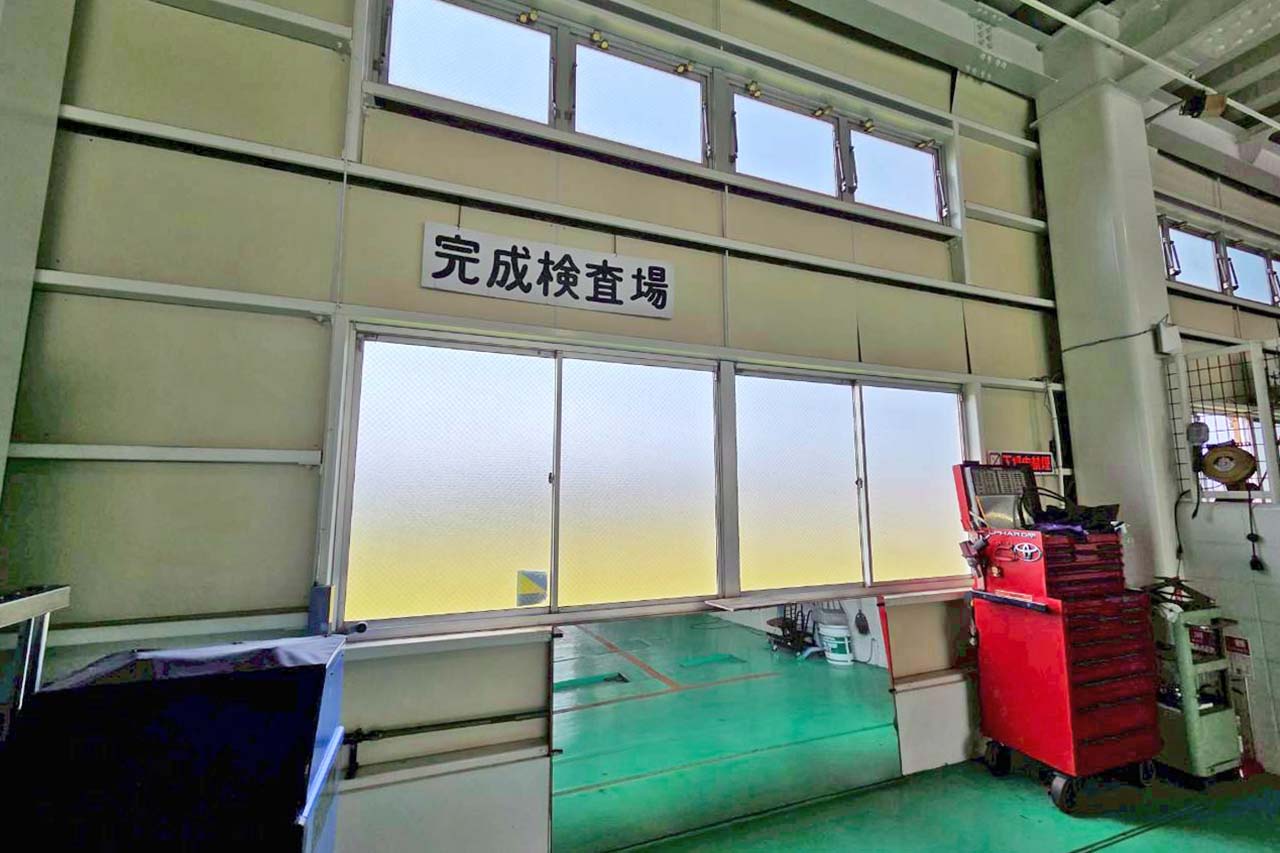 壁に「完成検査場」と掲示された、工具棚が設置されている自社工場内部の様子