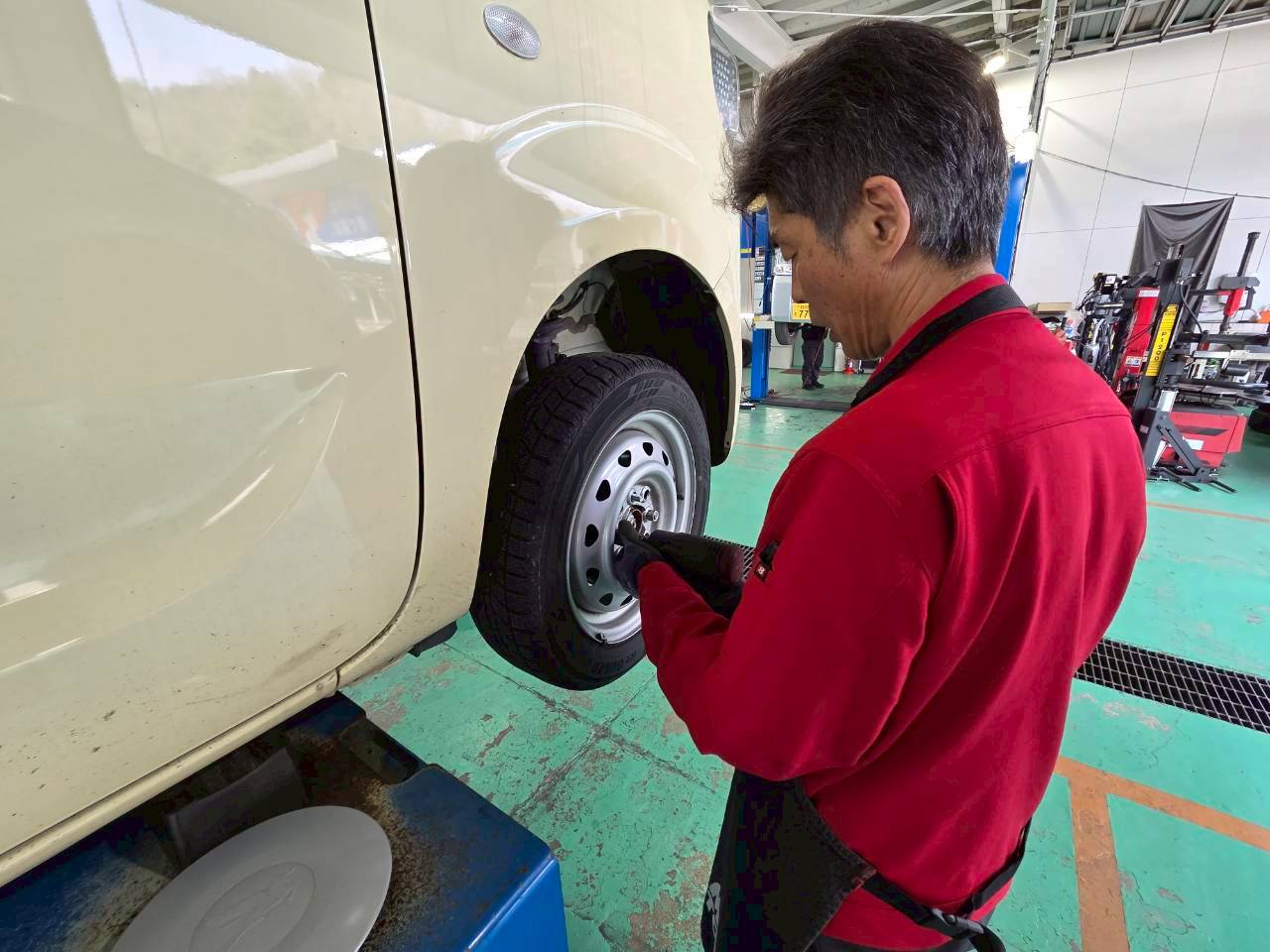 工具を使って車のタイヤを整備しているスタッフの手元