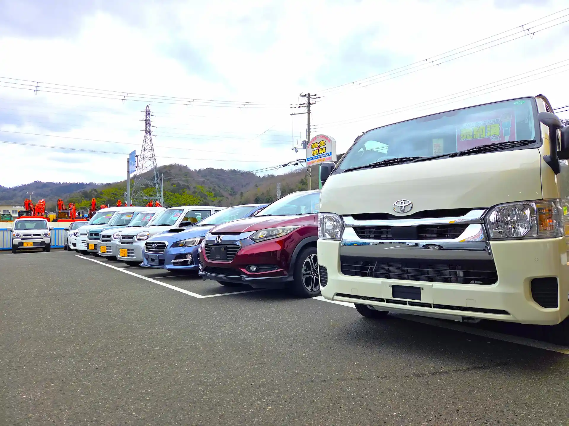 屋外の敷地に、軽自動車から普通車まで多様な車種の販売車両がずらりと並んでいる様子